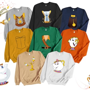 May include: Set of ten crewneck sweatshirts featuring characters from the Disney movie Beauty and the Beast. The sweatshirts are in various colors, including yellow, green, blue, white, and beige. Each sweatshirt features a different character, including Belle, Beast, Gaston, Lumiere, Cogsworth, Mrs. Potts, Chip, and the enchanted rose.