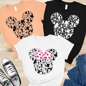 May include: Three t-shirts in peach, black, and white, each featuring a Mickey Mouse silhouette filled with character icons. The white shirt has a pink polka-dot bow. A pair of black and white sneakers and blue jeans are also visible.