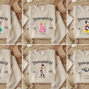 Puede incluir: Seis sudaderas beige con diferentes gr&aacute;ficos de personajes de Disney. Cada sudadera tiene el texto "Disneyworld est. 1971 FLORIDA".