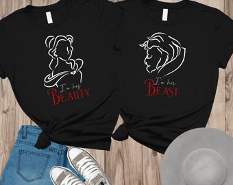 May include: Two black t-shirts with white line drawings of Beauty and the Beast. The Beauty shirt says "I'm his Beauty" in red script, and the Beast shirt says "I'm her Beast" in red script. The shirts are paired with blue jeans and sneakers.