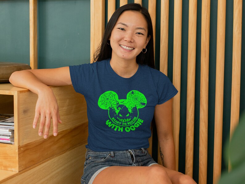 May include: A navy blue t-shirt with a green graphic of a Mickey Mouse head with a spiderweb design. The text "Ready to Boogie with Oogie" is printed below the graphic.