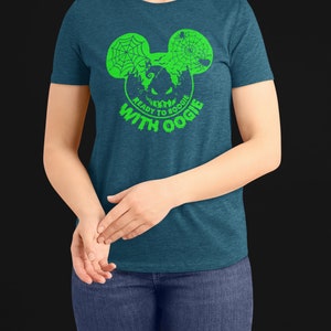 May include: A teal blue t-shirt with a green graphic of a Mickey Mouse head with a spider web and a pumpkin face inside. The text "Ready to Boogie with Oogie" is written below the graphic.