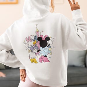 May include: White hooded sweatshirt with a graphic print of Mickey Mouse and Minnie Mouse in front of Cinderella's Castle.