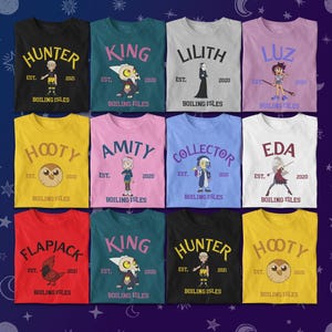 May include: A collection of colorful t-shirts featuring characters from "The Owl House" animated series. Each shirt displays a character's name, a graphic, and the text "BOILING ISLES". The shirts are in various colors, including black, teal, and yellow.