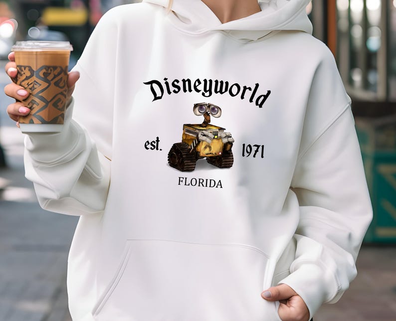 Puede incluir: Sudadera blanca con un gr&aacute;fico negro de un personaje robot de la pel&iacute;cula Wall-E. El gr&aacute;fico incluye el texto "Disneyworld est. 1971 Florida".