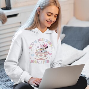 May include: White hoodie with a graphic of Mickey Mouse and Daisy Duck in a teacup. The text on the hoodie reads "Girls Just Wanna Have Fun!"