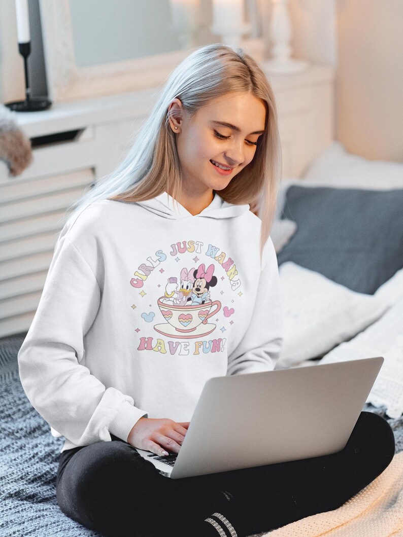 May include: White hoodie with a graphic of Mickey Mouse and Daisy Duck in a teacup. The text on the hoodie reads "Girls Just Wanna Have Fun!"