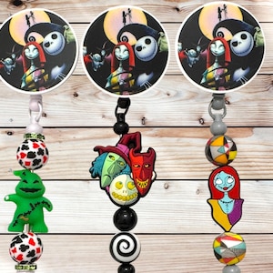 May include: Three retractable badge holders featuring characters from The Nightmare Before Christmas. Each holder has a different charm, including Oogie Boogie, a trio of villains, and Sally. The badge reels have a wooden background.