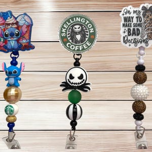 May include: Three badge reels with different designs. One features Stitch from Lilo & Stitch with a dessert theme. Another has a Jack Skellington design with a coffee theme. The third has a leopard print mug and the text "On my way to make some bad decisions."