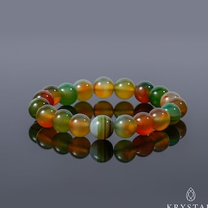 K&ouml;nnte beinhalten: Ein mehrfarbiges Agat-Armband mit gr&uuml;nen, orangefarbenen und braunen Perlen. Das Armband besteht aus nat&uuml;rlichen Steinen und hat eine polierte Oberfl&auml;che.