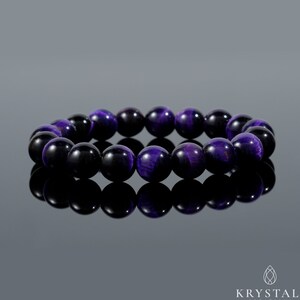 May include: A beaded bracelet featuring polished, round beads in shades of deep purple and black. The bracelet is displayed on a reflective surface, showcasing the jewelry's color and design. The beads appear to be approximately 0.4 inches in diameter.