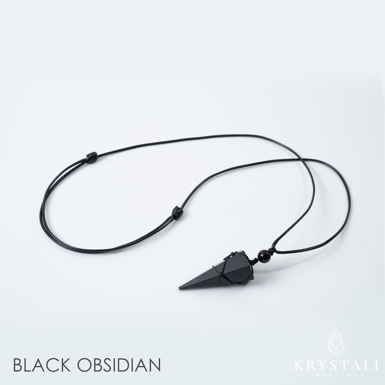 May include: Black obsidian pendant necklace with a pointed, geometric shape. The pendant is suspended from a black cord with adjustable knots. The text "BLACK OBSIDIAN" is at the bottom of the image.