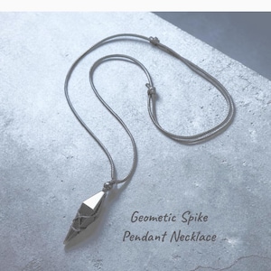 May include: A silver-toned geometric spike pendant necklace. The pendant has a faceted design and is suspended from a delicate chain. The text "Geometric Spike Pendant Necklace" is visible.