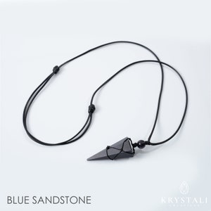 May include: A black necklace featuring a triangular blue sandstone pendant. The pendant is suspended from a black cord with adjustable knots. The words "BLUE SANDSTONE" are printed at the bottom of the image.