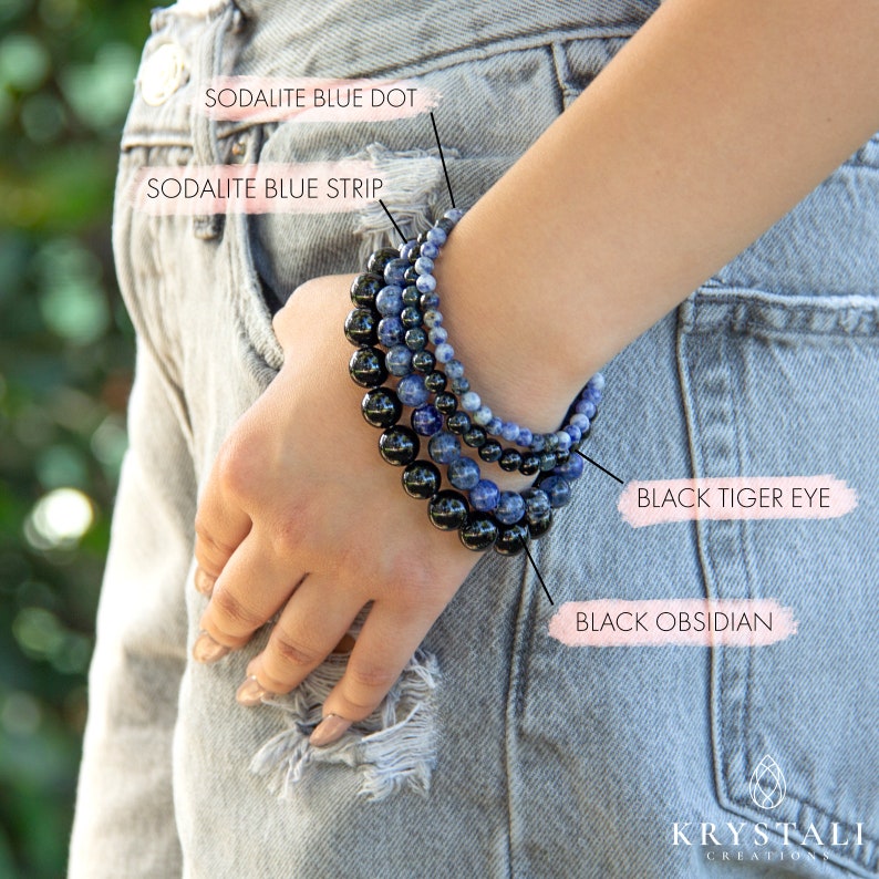 Op de afbeelding: Een stapel van vier kralenarmbanden om een pols. De armbanden zijn gemaakt van zwarte obsidiaan, zwarte tijgeroog, blauwe sodaliet met stippen en blauwe sodaliet met strepen.