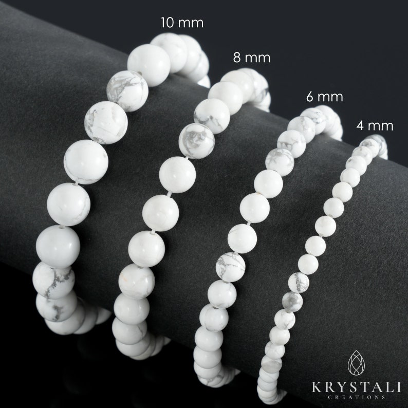 May include: Four white Howlite bead bracelets in different sizes: 4 mm, 6 mm, 8 mm, and 10 mm. The bracelets are arranged in a row on a black surface.