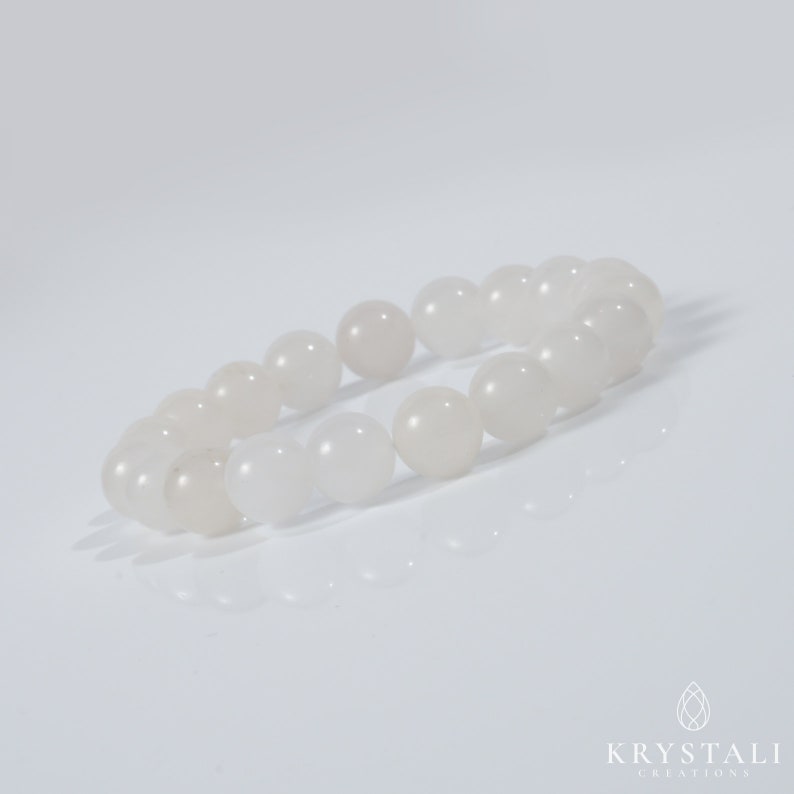 May include: A white gemstone bracelet with round beads. The bracelet is made of natural white stones and is designed to be worn on the wrist.
