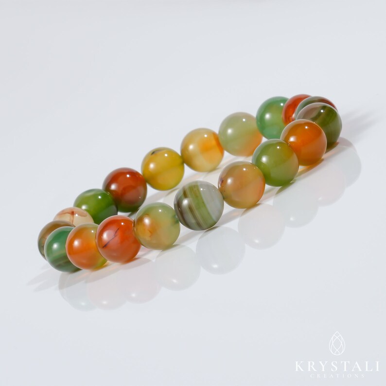 K&ouml;nnte beinhalten: Ein mehrfarbiges Agat-Armband mit gr&uuml;nen, orangefarbenen und roten Perlen. Das Armband besteht aus nat&uuml;rlichen Steinen und ist ein wundersch&ouml;nes und einzigartiges Schmuckst&uuml;ck.