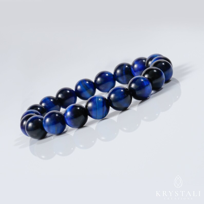 May include: A blue tiger's eye beaded bracelet. The beads are round and have a dark blue color with a subtle shimmer.