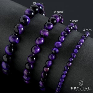 May include: Four purple tiger eye bead bracelets, with bead sizes of 4 mm, 6 mm, 8 mm, and 10 mm. The bracelets are displayed on a dark gray surface. The KRYSTALI CREATIONS logo is in the bottom right corner.