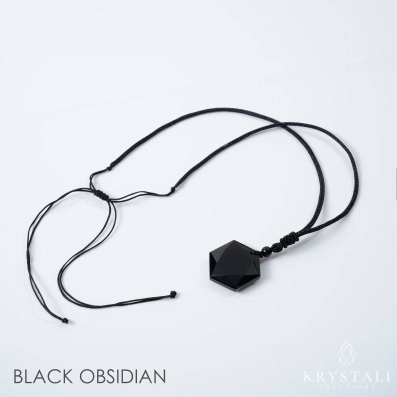 K&ouml;nnte beinhalten: Eine Halskette mit einem Anh&auml;nger aus schwarzem Obsidian. Der Anh&auml;nger hat eine facettierte, geometrische Form und h&auml;ngt an einer schwarzen Kordel. Die Kordel ist mit Schiebeknoten verstellbar. Der Text "BLACK OBSIDIAN" befindet sich unten im Bild.