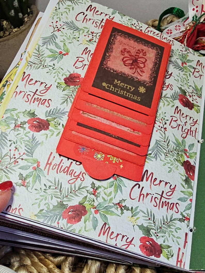 Może przedstawiać: Stos czerwono-brązowych kartek świątecznych z zielono-białym wzorem kwiatowym. Na kartkach widnieje napis "Merry Christmas" i "Holidays".