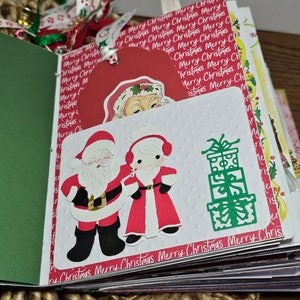 Może przedstawiać: Album scrapbookingu o tematyce świątecznej z białą stroną przedstawiającą Świętego Mikołaja i Panią Mikołajową w czerwieni i bieli, zielony stos prezent&oacute;w oraz tekst "Merry Christmas Merry Christmas Merry Christmas Merry Chris".