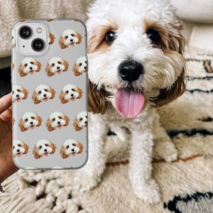 May include: A clear phone case with a repeating pattern of a dog's face. The dog has brown and white fur and is looking directly at the camera. The phone case is on a white and brown rug.