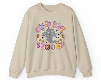 Może przedstawiać: Beżowa bluza z nadrukiem graficznym ducha z tekstem "Cute But Spooky" w kolorowych literach.