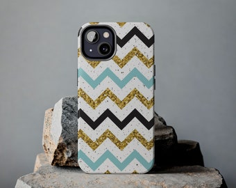 Puede incluir: Una funda de teléfono blanca con un patrón de chevron negro y azul y detalles de purpurina dorada. La funda tiene un recorte para la cámara del teléfono.