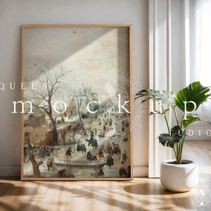 May include: A framed painting depicting a winter scene with people ice skating on a frozen lake. The painting is in a wooden frame and is hanging on a white wall. There is a potted plant in the foreground.