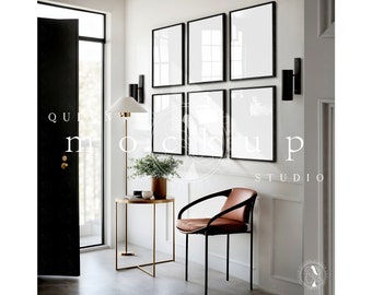 May include: A white wall with six black framed pictures, a brown leather chair, a gold metal side table, a floor lamp, and a black door.