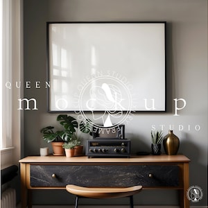 May include: A black framed picture hangs on a gray wall above a wooden desk with a black drawer. The desk has a black and gold vase, a vintage stereo, and three potted plants on top. The text "QUEEN MOCKUP STUDIO" is visible on the wall.