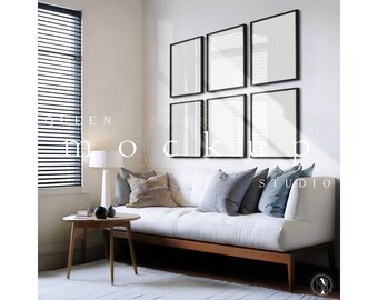 May include: A modern living room setup featuring a white sofa with wooden legs, adorned with decorative pillows. Six black-framed blank art prints are mounted on the wall. A small round wooden side table and a white floor lamp complete the scene.