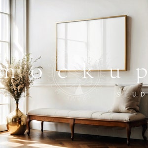 Pode incluir: Uma imagem emoldurada em ouro pendurada em uma parede branca acima de um banco de madeira com uma almofada branca. Um vaso com flores secas fica no canto da sala.