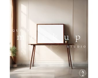 May include: A wooden table with a brown frame and three legs. A white framed picture sits on top of the table. A small potted plant sits on the table to the right of the picture.