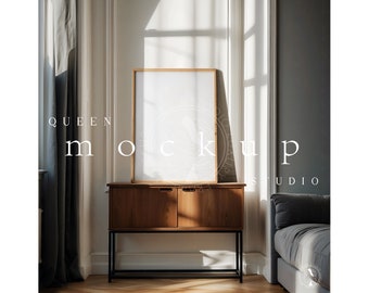 May include: A wooden frame with a white background sits on a wooden cabinet with black metal legs. The cabinet is in a room with gray walls and a window with white curtains. The text "QUEEN MOCKUP STUDIO" is visible in the image.