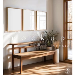 May include: Three gold framed rectangular wall art prints hanging on a white wall above a wooden bench with a vase of dried wheat and a potted plant. The text "QUEEN FRAME STUDIO" is visible on the wall.