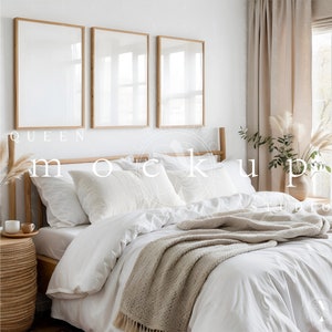 May include: A white queen-sized bed with a white duvet cover and a beige throw blanket. The bed is styled with white and beige pillows. Three framed pictures hang on the wall behind the bed. The room is decorated in a minimalist style with a wooden bedside table and a vase of dried pampas grass.