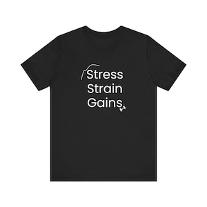 Puede incluir: Camiseta negra con la frase blanca "Stress Strain Gains" y un gráfico. La camiseta tiene cuello redondo y parece estar hecha de un material suave.