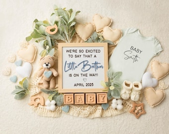 以下が含まれることがあります： 「We're so excited to say that a Little Brother is on the way! April 2025」と書かれた看板のあるベビー発表。看板の周りは、ロンパース、ベビーシューズ、ぬいぐるみなど、さまざまなベビー用品で囲まれています。