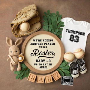 Może przedstawiać: Brązowy drewniany znak z tekstem "We're adding another player to our Roster Baby #3 Up to bat in April". Znak jest otoczony przez rękawicę baseballową, piłkę baseballową, pluszowego króliczka trzymającego kij, dziecięcy śpioszek z napisem "Thompson 03", dwa dziecięce buciki i zieloną roślinę.