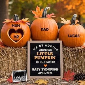 May include: Three orange pumpkins with leaf accents sit on a hay bale. The pumpkins are labeled "MOM," "DAD," and "LUCAS." The first pumpkin has a heart-shaped cutout with a smaller pumpkin inside, labeled "#2." A sign reads "We're adding another little pumpkin."