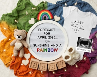May include: A white letter board with the text "FORECAST FOR APRIL 2025... SUNSHINE AND A RAINBOW" surrounded by a rainbow coloured fabric, a teddy bear, wooden blocks spelling "BABY", and a white onesie with the text "BABY Richardson" and a heart.