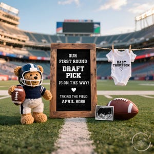May include: A charming announcement on a football field. A crocheted teddy bear in a football helmet and uniform holds a football. A sign reads "OUR FIRST ROUND DRAFT PICK IS ON THE WAY! TAKING THE FIELD APRIL 2026." A baby onesie and ultrasound image are also displayed.
