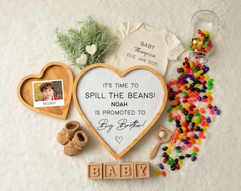 May include: A wooden heart-shaped sign with the text "It's time to spill the beans! Noah is promoted to Big Brother!"  A photo of a young boy in a heart-shaped frame, a baby onesie with the text "Baby Thompson Due Jan 2025", wooden blocks spelling "BABY", a jar of jelly beans, and a pair of brown baby booties.