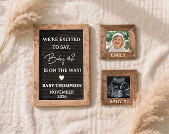May include: A pregnancy announcement featuring a framed felt letter board with the text "We're excited to say, Baby #2 is on the way!" and a heart symbol. Two small wooden frames display a photo of a child and a sonogram.