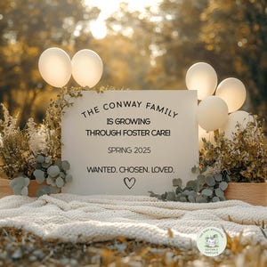 May include: A white sign with black text announcing "The Conway Family is Growing Through Foster Care! Spring 2025 Wanted. Chosen. Loved."  The sign is surrounded by white balloons and greenery.