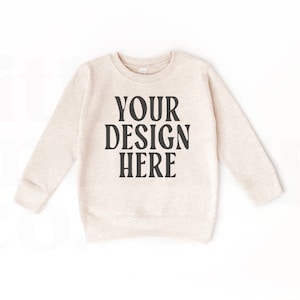 May include: A beige crewneck sweatshirt with long sleeves. The text "YOUR DESIGN HERE" is printed in bold black letters across the front. The sweatshirt is displayed on a white background.