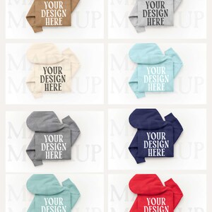 May include: Folded hoodies in a range of colours: tan, grey, cream, light blue, dark grey, navy, teal, and red. Each hoodie displays the text "YOUR DESIGN HERE" in white, bold font, centrally placed on the front.
